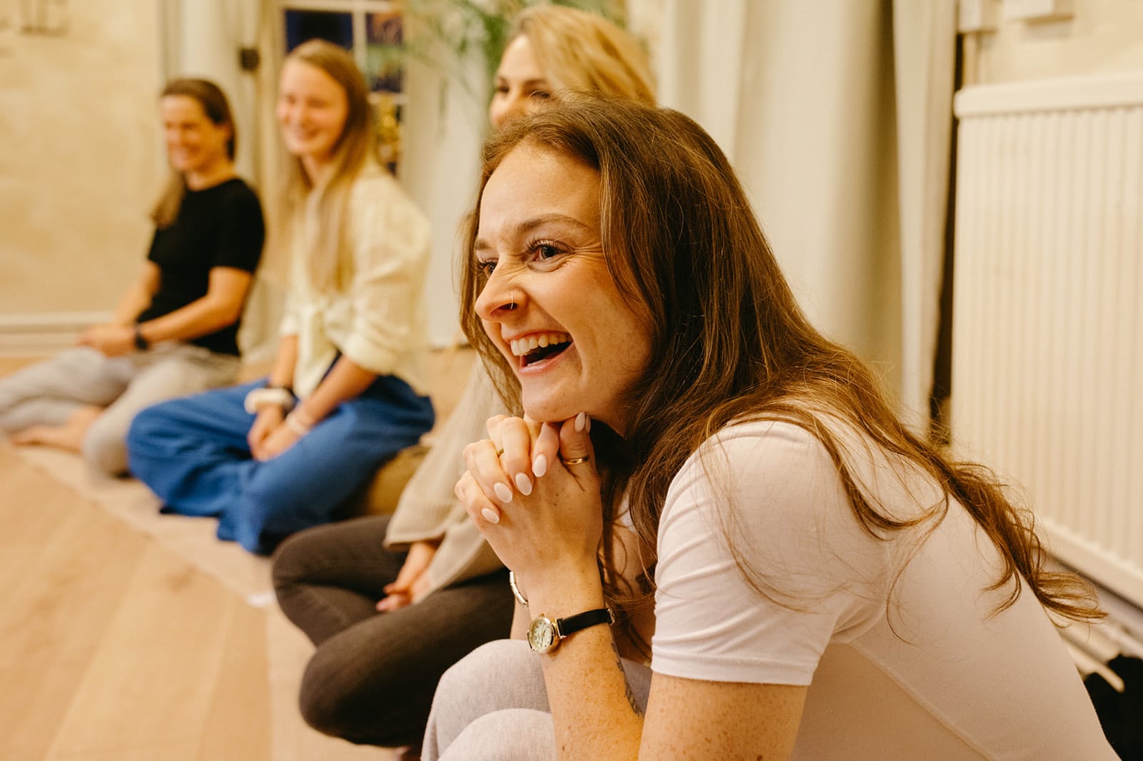 A trainee laughs with joy, hands clasped, during the closing circle
