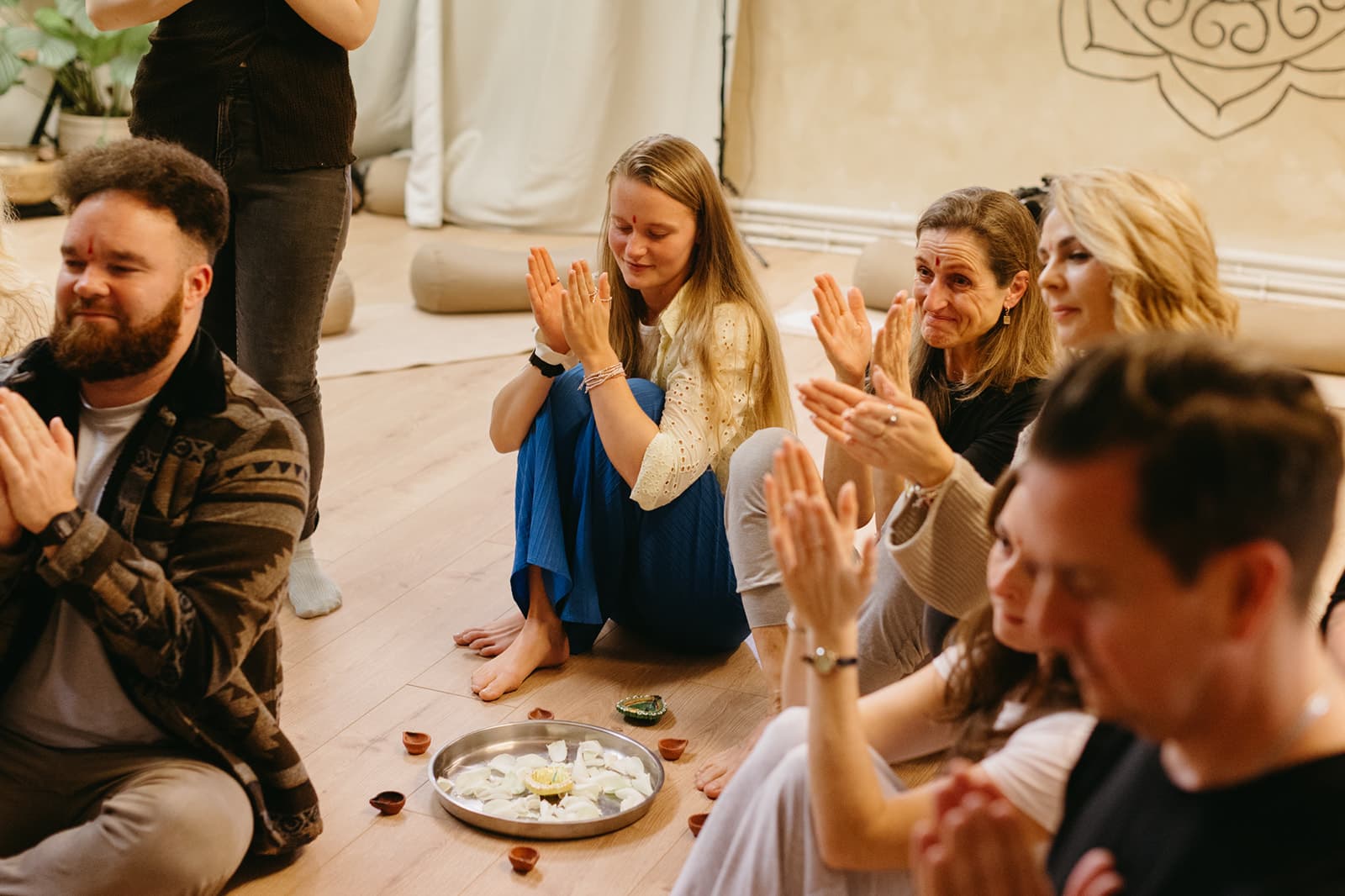 Trainees applauding around a brass plate of lit diyas