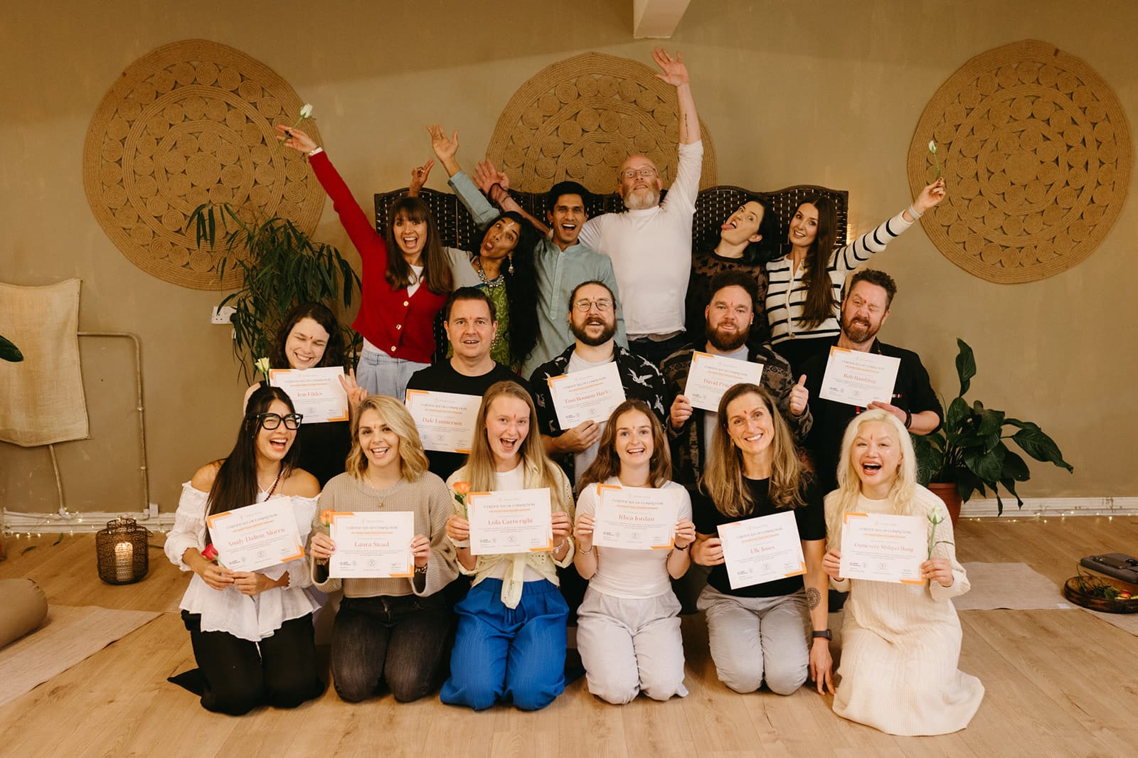 Graduates cheering with arms raised and certificates in hand