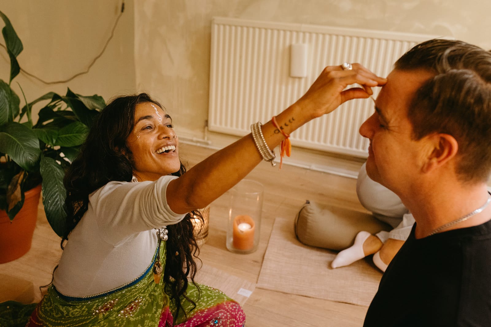A teacher smiles as she marks a trainee’s forehead with tilak