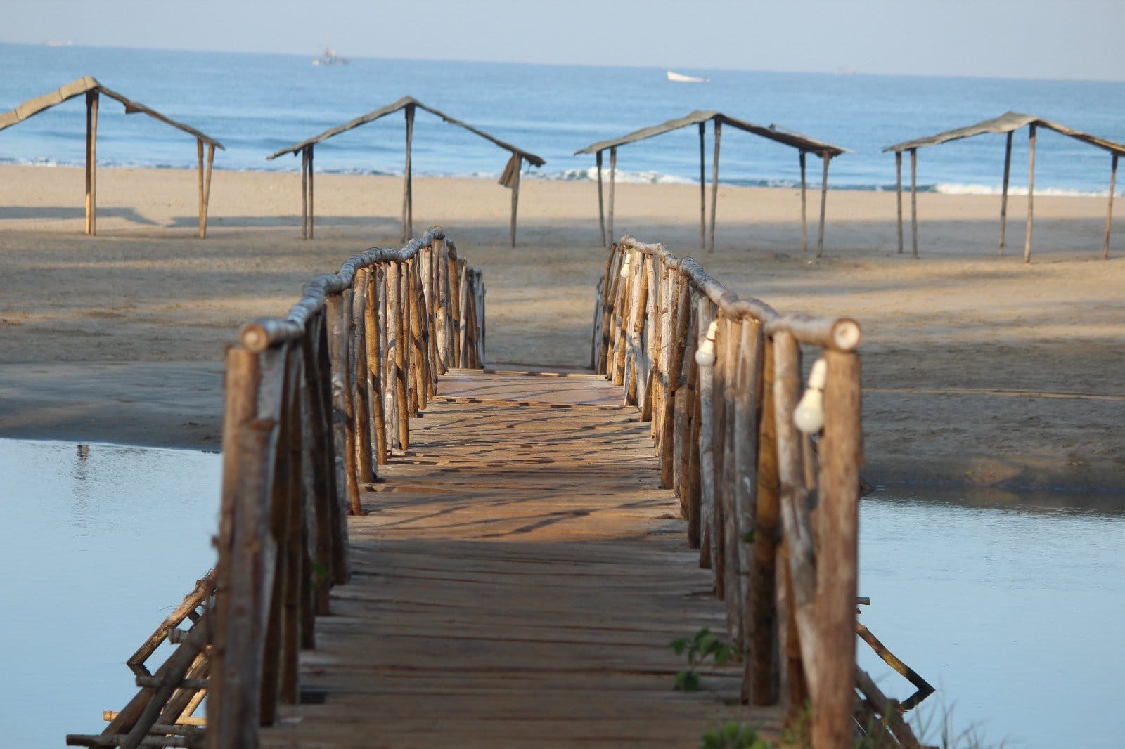 A wooden footbridge leading towards beach huts