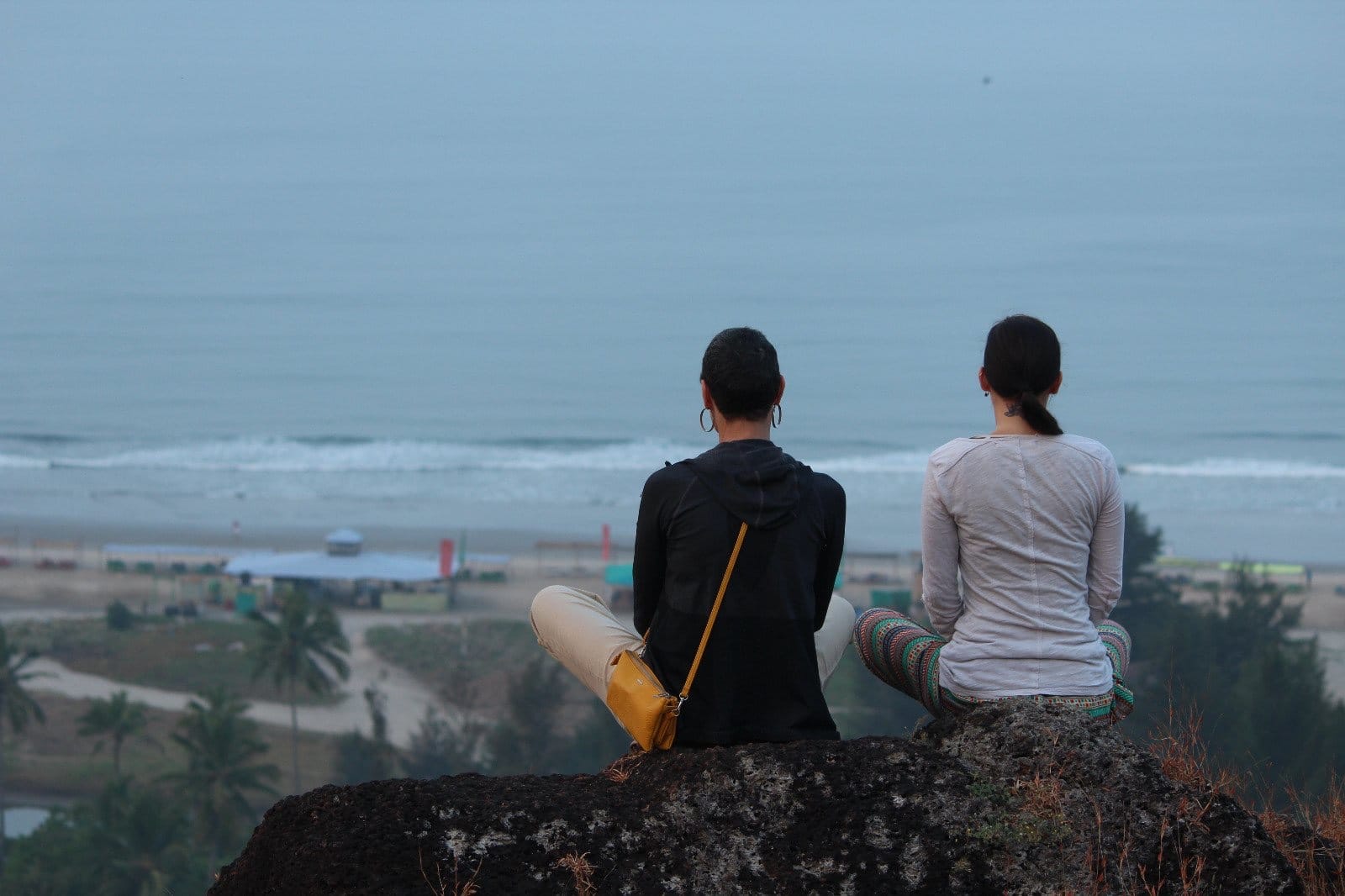 Two women sitting on rocks overlooking the beach